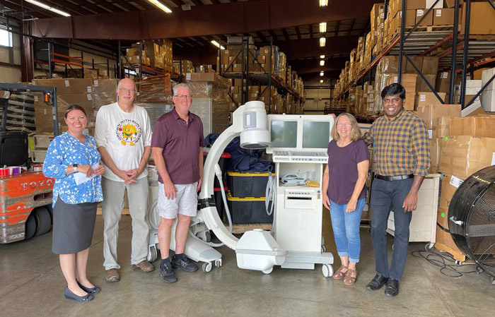 Mission Outreach team stands next to imaging equipment in their warehouse