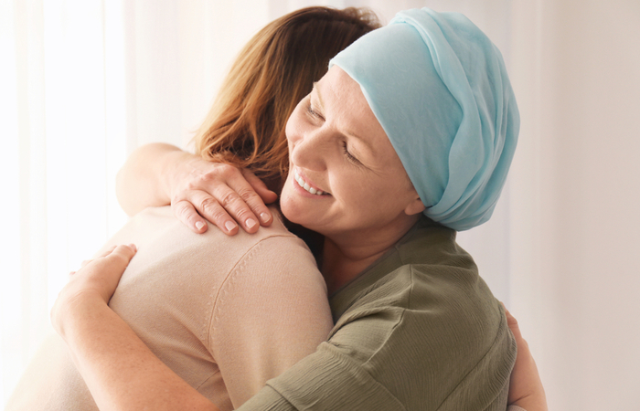 Woman wearing a turban hugging another woman in a living room