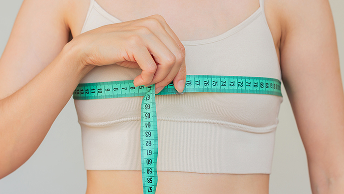 woman holding tape measure around her breasts