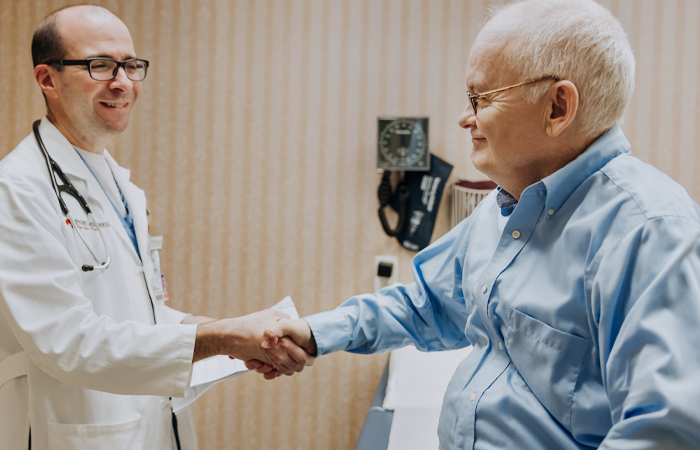 Male doctor shaking elderly man's hand