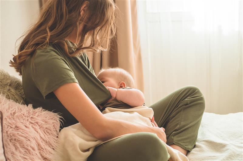 woman with long dark brown hair breastfeeding a young infant