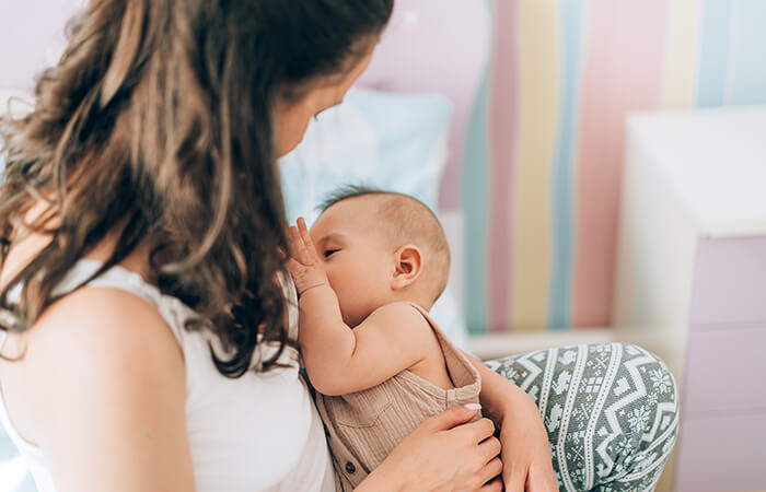 woman with long dark brown hair breastfeeding a young infant