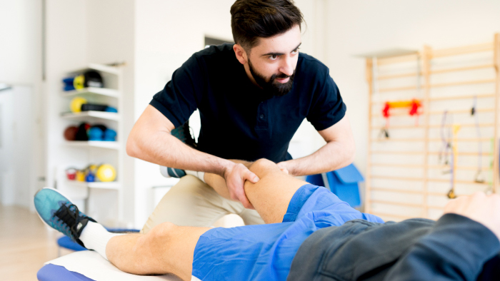 Young male therapists evaluating man's knee