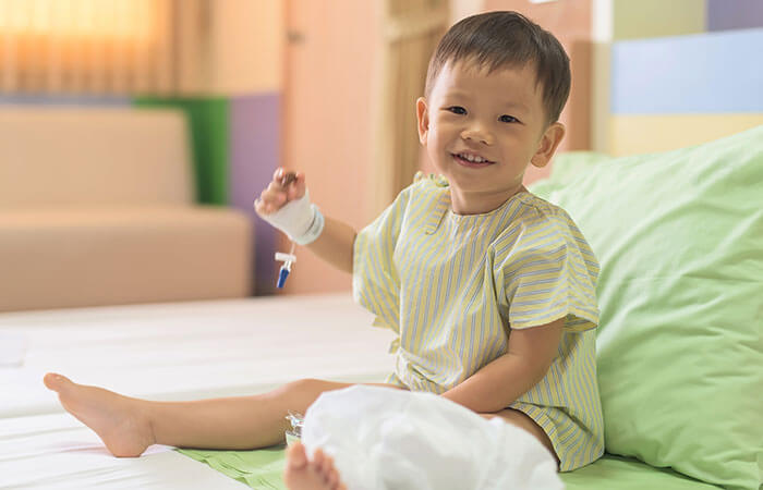 young child sitting in hospital bed and smiling at the camera