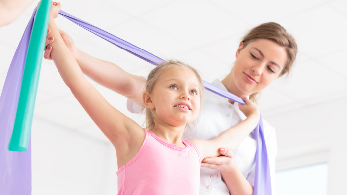 Young girl with stretching bands working with therapist