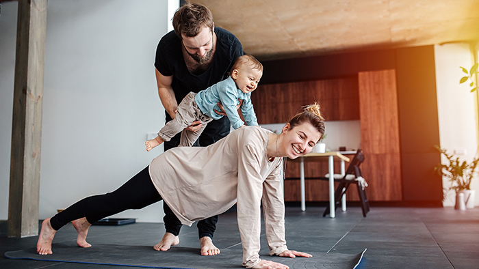 Mom doing a push-up with dad helping baby