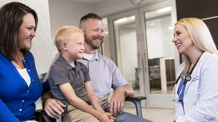 Young family in waiting room talking with female health care worker