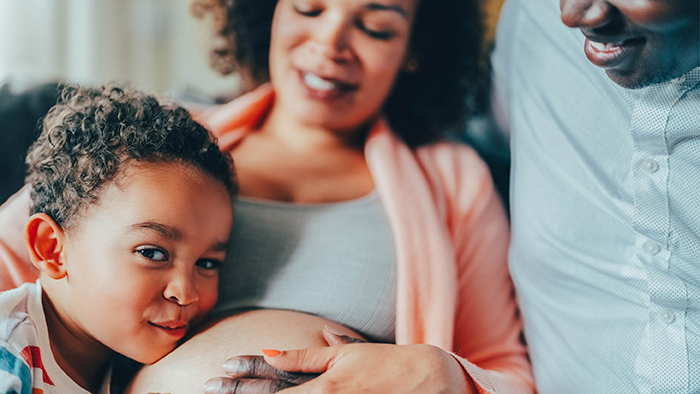 little kid resting head on expecting mother's belly