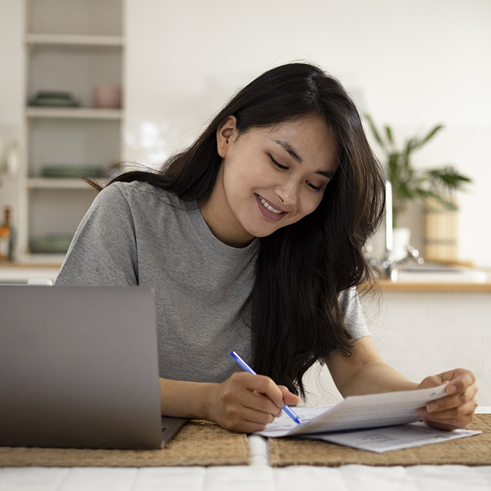 Young women sits at a desk while reviewing and paying her bill online