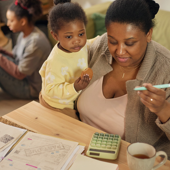 A mom holding her baby while looking at a calculator