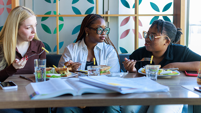 three young women talking and having lunch