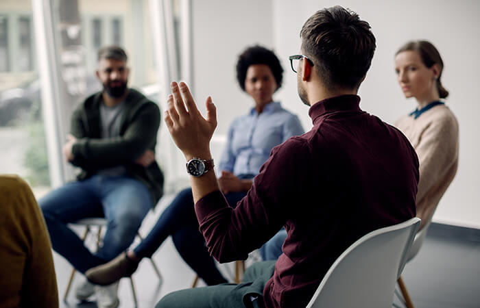 a male speaking in a diverse support group with 5 other members