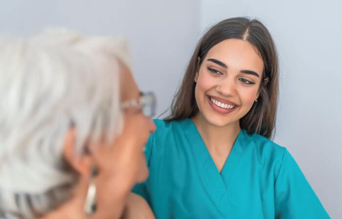 young nurse speaking to elderly patient in hospital room
