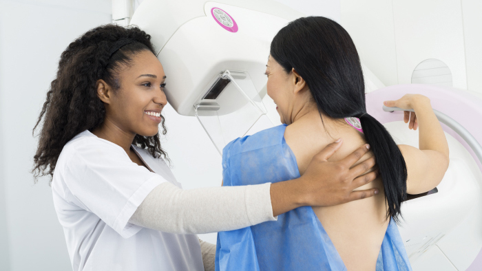 Woman mammography technician performing a mammogram on young woman