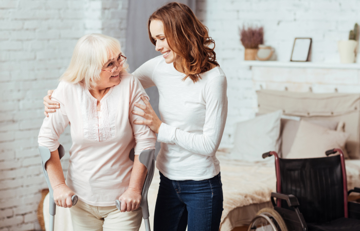 young woman assisting older woman using crutches