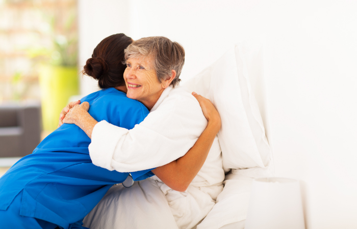 black nurse hugging elderly white woman 