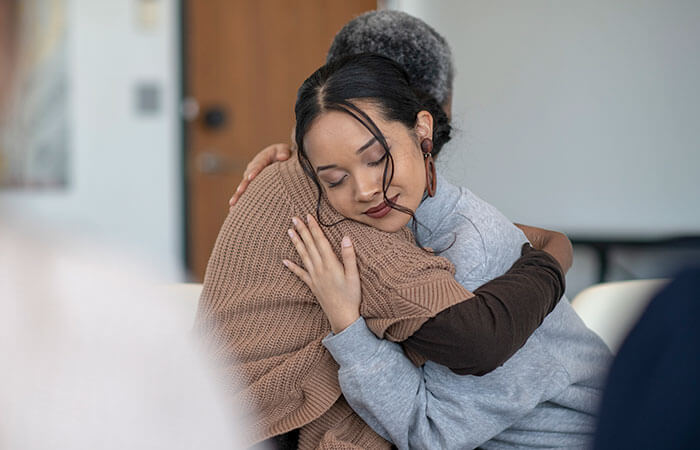 Young woman hugging a middle aged woman in a room