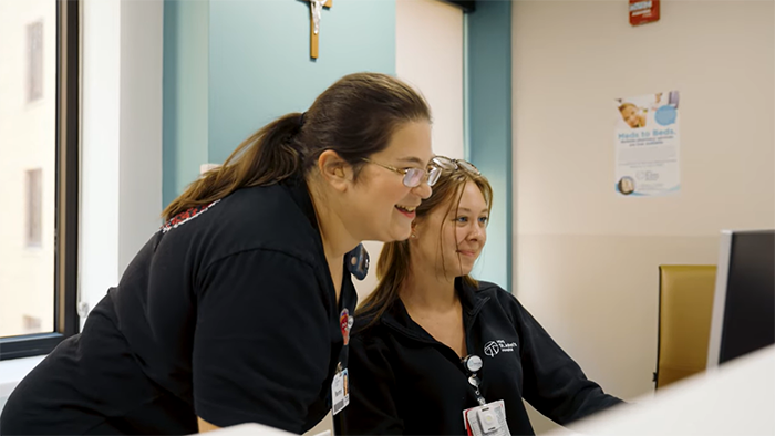 two patient care assistants looking at computer monitor