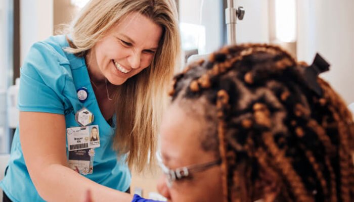 Smiling nurse preparing infusion therapy for a female patient