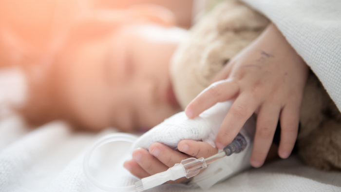 Young child sleeping with IV in hand holding teddy bear